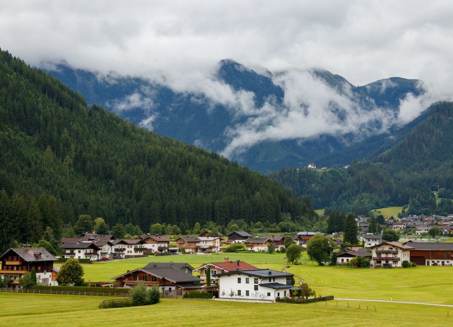 Charming alpine village nestled in lush, misty mountains on a cloudy day.