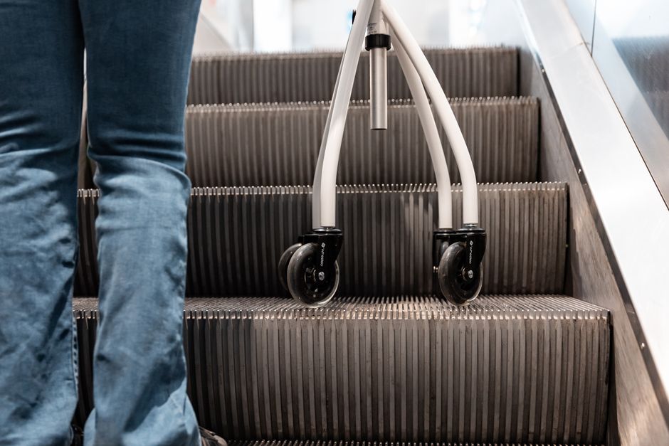 A person using a rollator navigates an escalator, emphasizing mobility support.