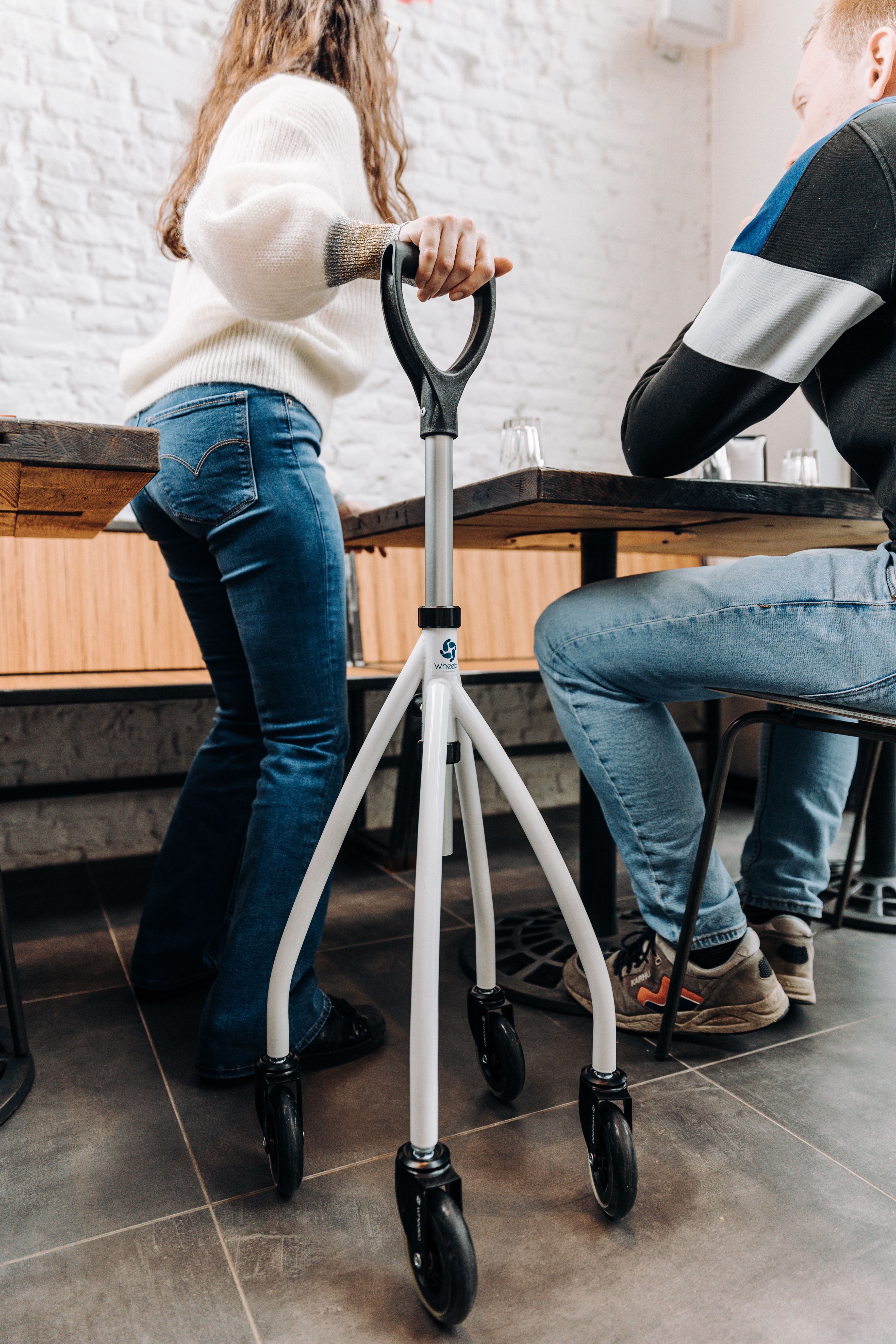 A person using a mobility aid rollator in a cozy cafe setting indoors.