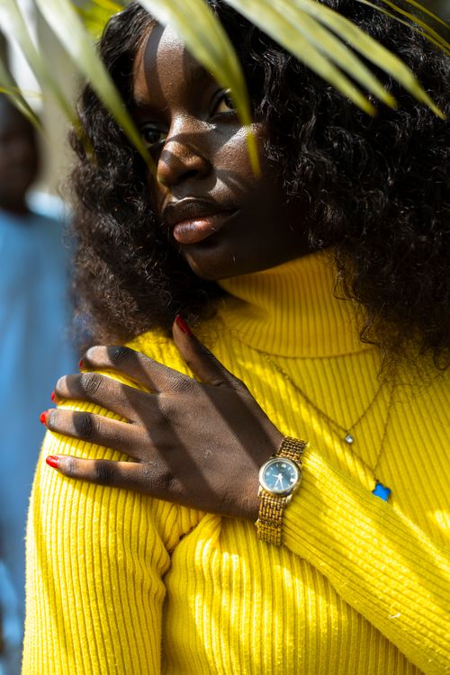 Free Close-up of a woman wearing a yellow sweater and gold watch, outdoors. Stock Photo