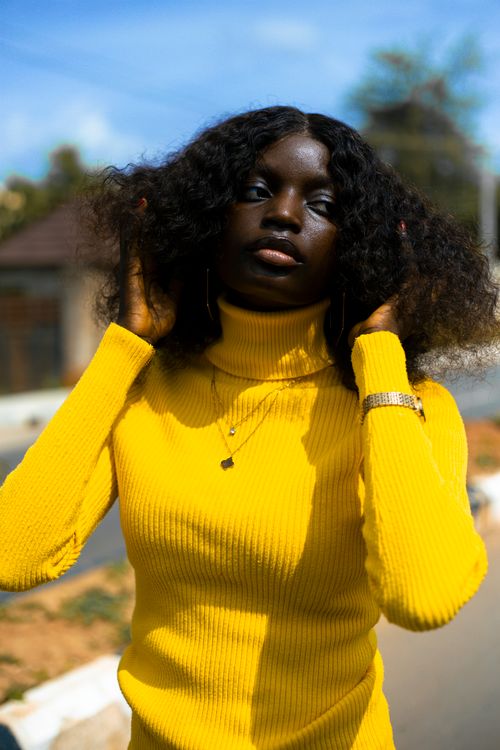 Free Stylish woman in yellow sweater posing outdoors with natural sunlight. Stock Photo
