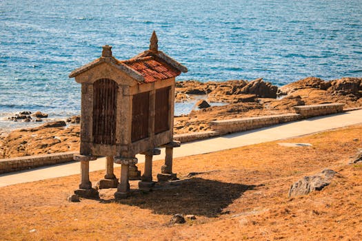 A traditional Galician hórreo stands by the rocky coast of Baiona, Spain.