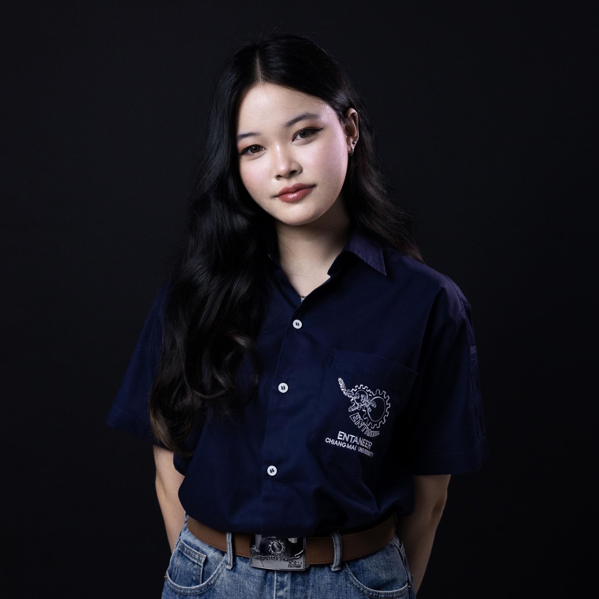 Young woman with long hair in a dark blue shirt, confident pose.