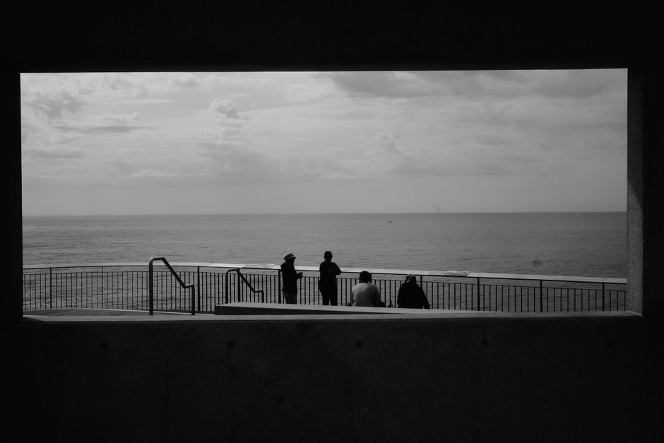 Black and white photo capturing silhouettes of people gazing at the ocean in Sydney, Australia.