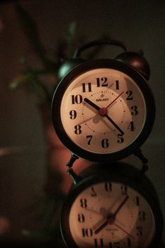 A classic alarm clock reflected on a glass surface, creating a retro ambiance.