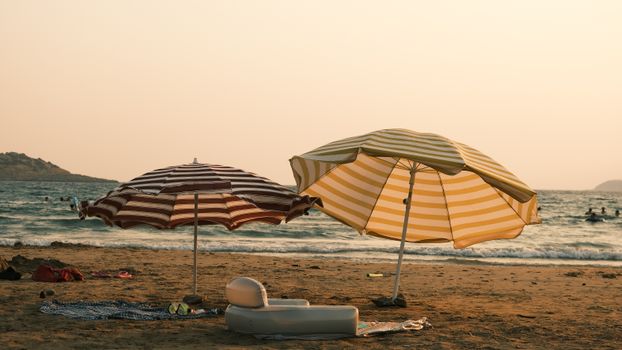Sunny beach with striped umbrellas and serene ocean waves, perfect for a summer escape.