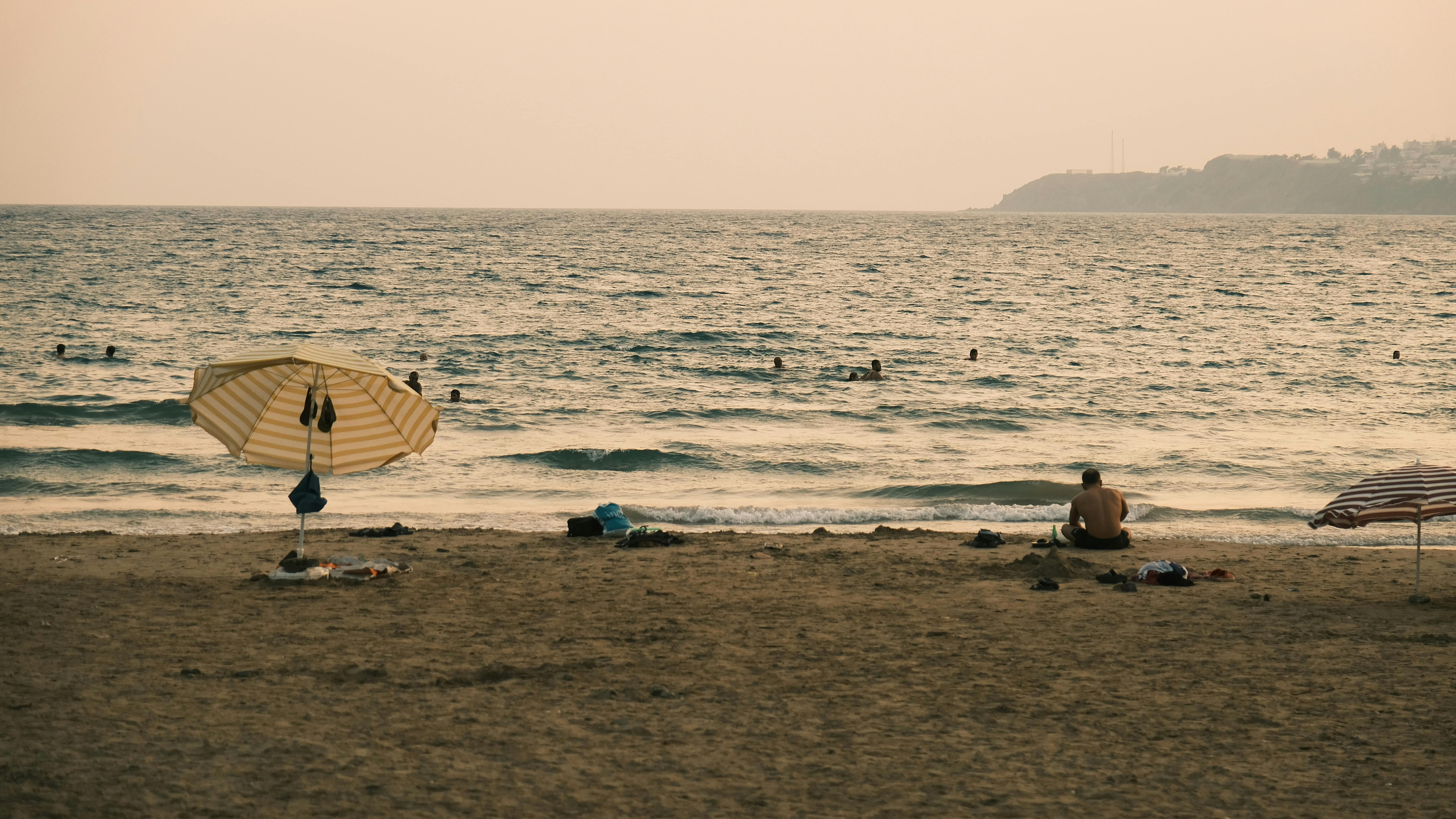 Beanbag seating on the sand at a Canggu beach bar with sunset light over Batu Bolong, Bali