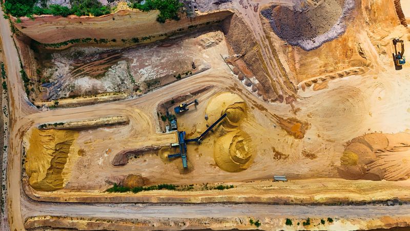 Aerial shot of a quarry with machinery extracting and processing materials.
