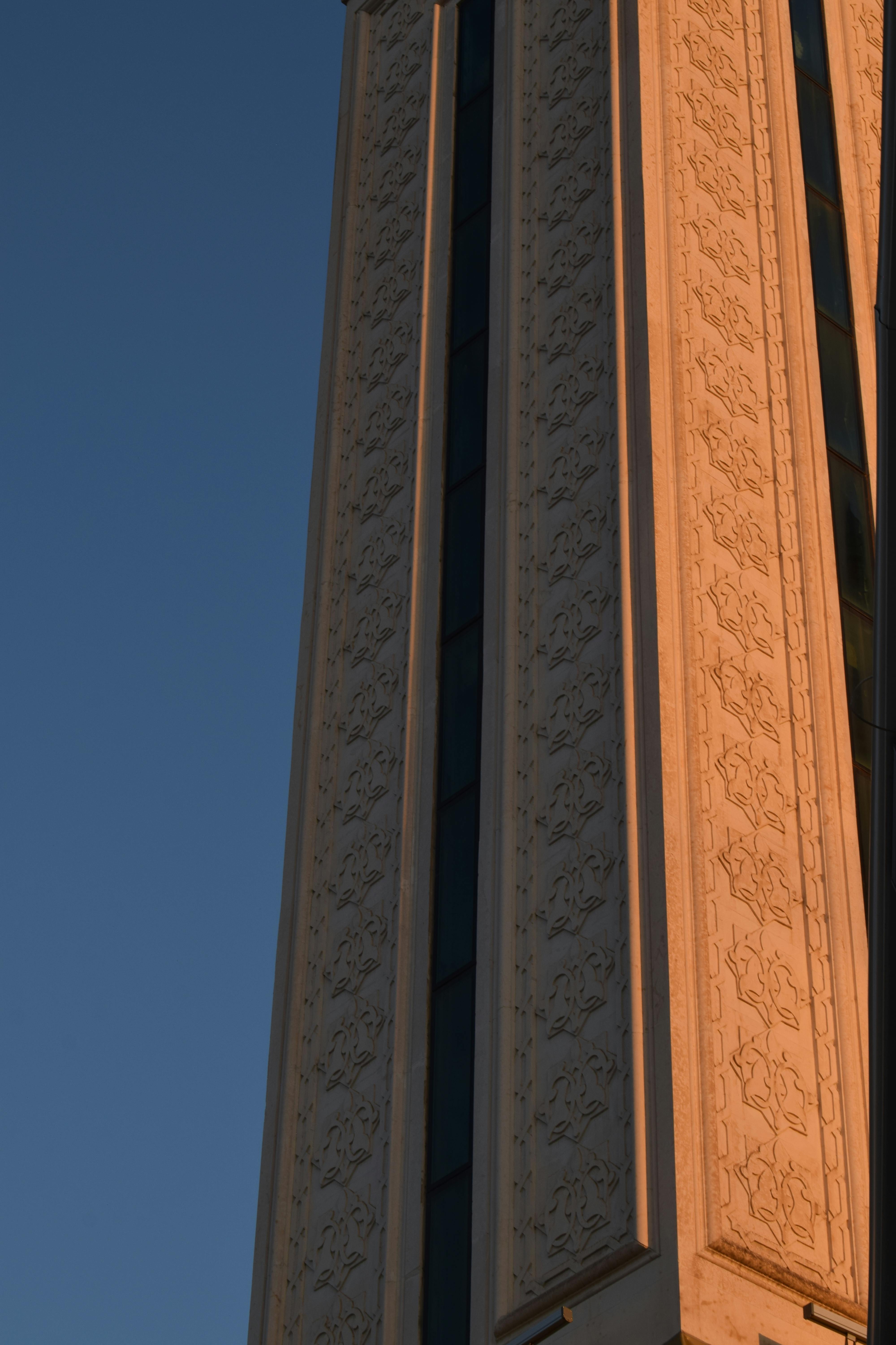 Kostenlos Nahaufnahme einer eleganten Gebäudefassade mit komplizierten Mustern, beleuchtet vom Licht des Sonnenuntergangs. Stock-Foto