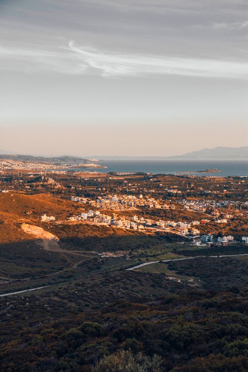 Free A breathtaking aerial view of a coastal town enveloped in golden sunlight, with the sea in the background. Stock Photo