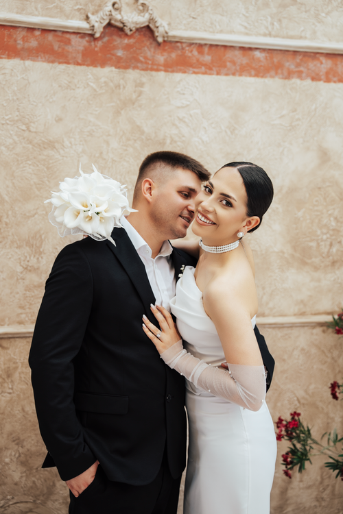 Free Happy newlyweds embracing in elegant attire, sharing a joyful moment indoors. Stock Photo