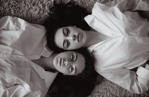 Free Monochrome artistic portrait of two women laying on carpet, showcasing expression and connection. Stock Photo