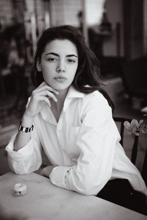 Free Black and white portrait of a woman in a white shirt, showcasing elegance and poise. Stock Photo