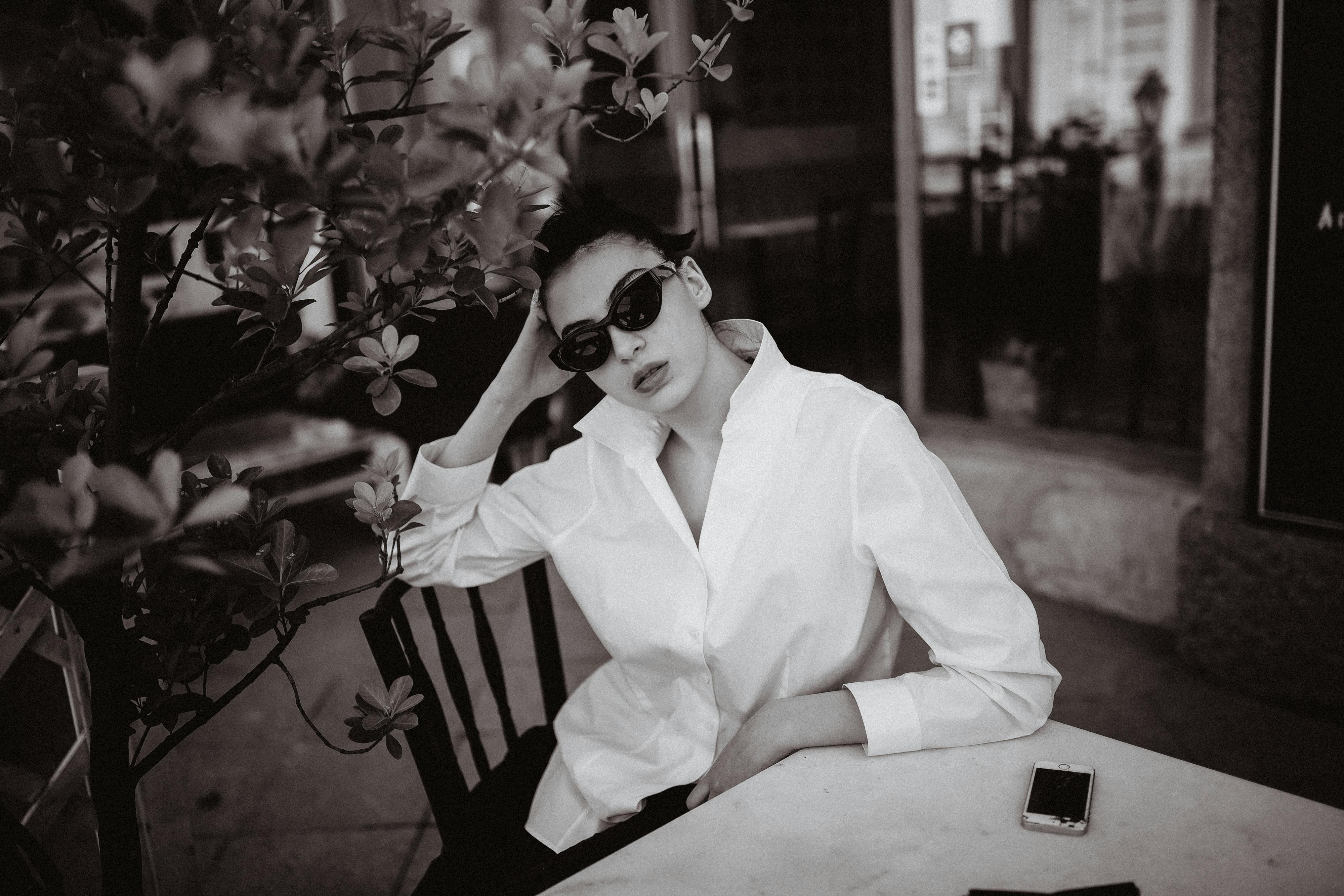 A stylish monochrome portrait of a woman in a white shirt and sunglasses — modern classic style