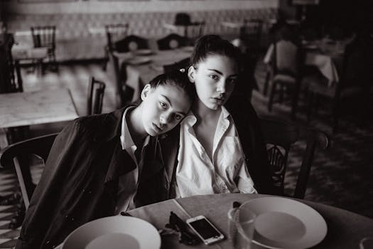 Intimate black and white portrait of two women seated in a restaurant setting, evoking a vintage vibe.