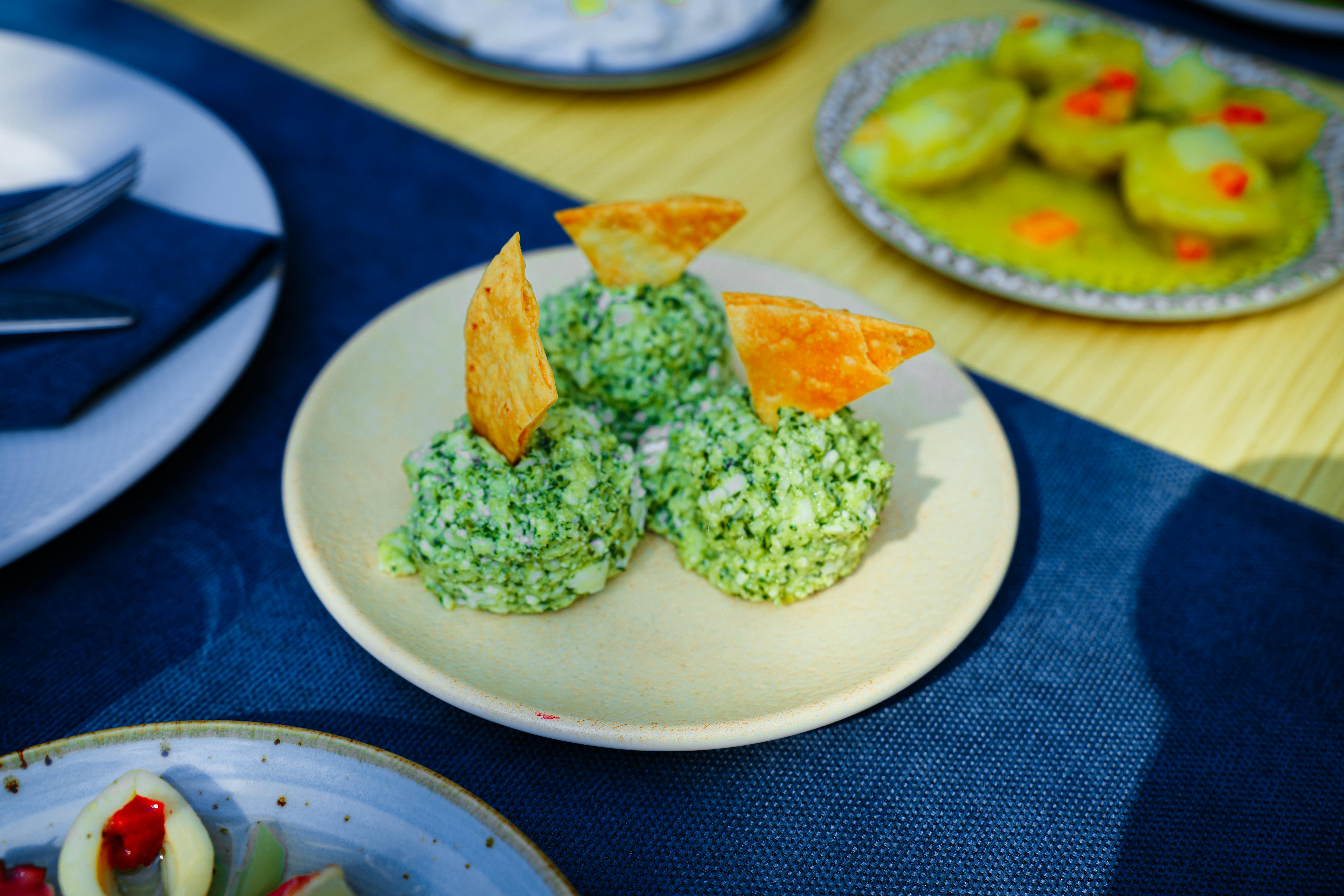 Plate of green cheese balls garnished with crispy chips on an outdoor table. - Photo by Busenur Demirkan on Pexels