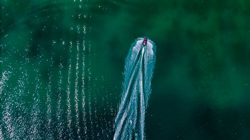Free High-angle aerial shot of a jetski creating waves on vibrant turquoise water in Sivrice, Türkiye. Stock Photo