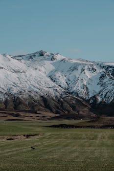 Stunning snow-covered mountains with a lush green valley below, captured during the day.