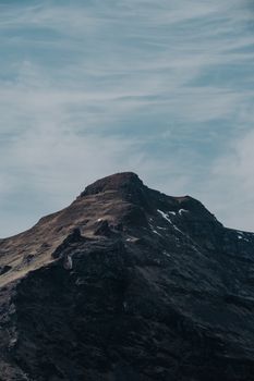 Majestic mountain peak reaching into cloudy sky in a dramatic landscape. Ideal for nature and travel themes.