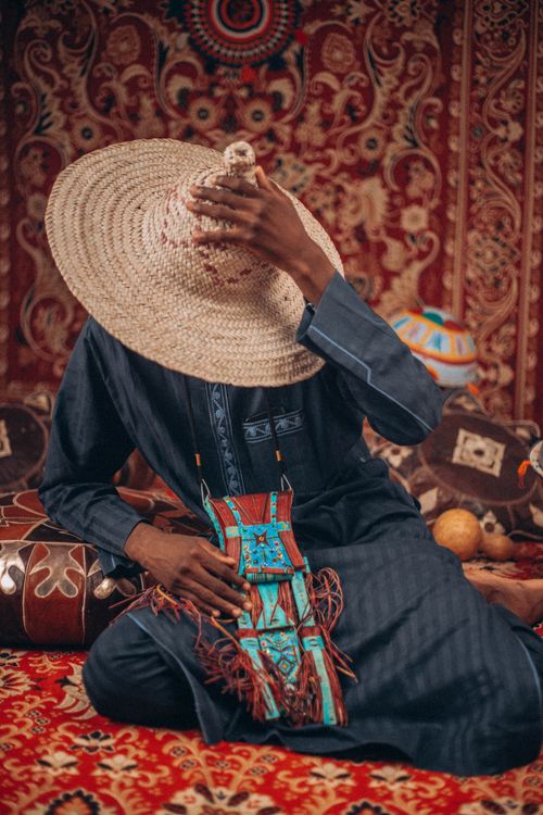 Free Person in traditional attire with a woven hat, showcasing cultural patterns and colors. Stock Photo