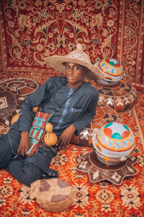 Free Man in traditional outfit with ethnic decor items, lying on ornate rugs. Stock Photo