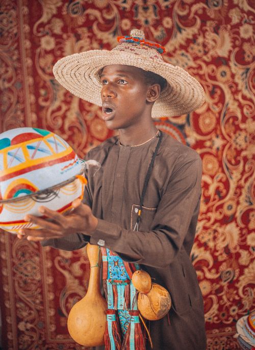 Free Young African man in traditional attire holding a colorful traditional drum. Stock Photo