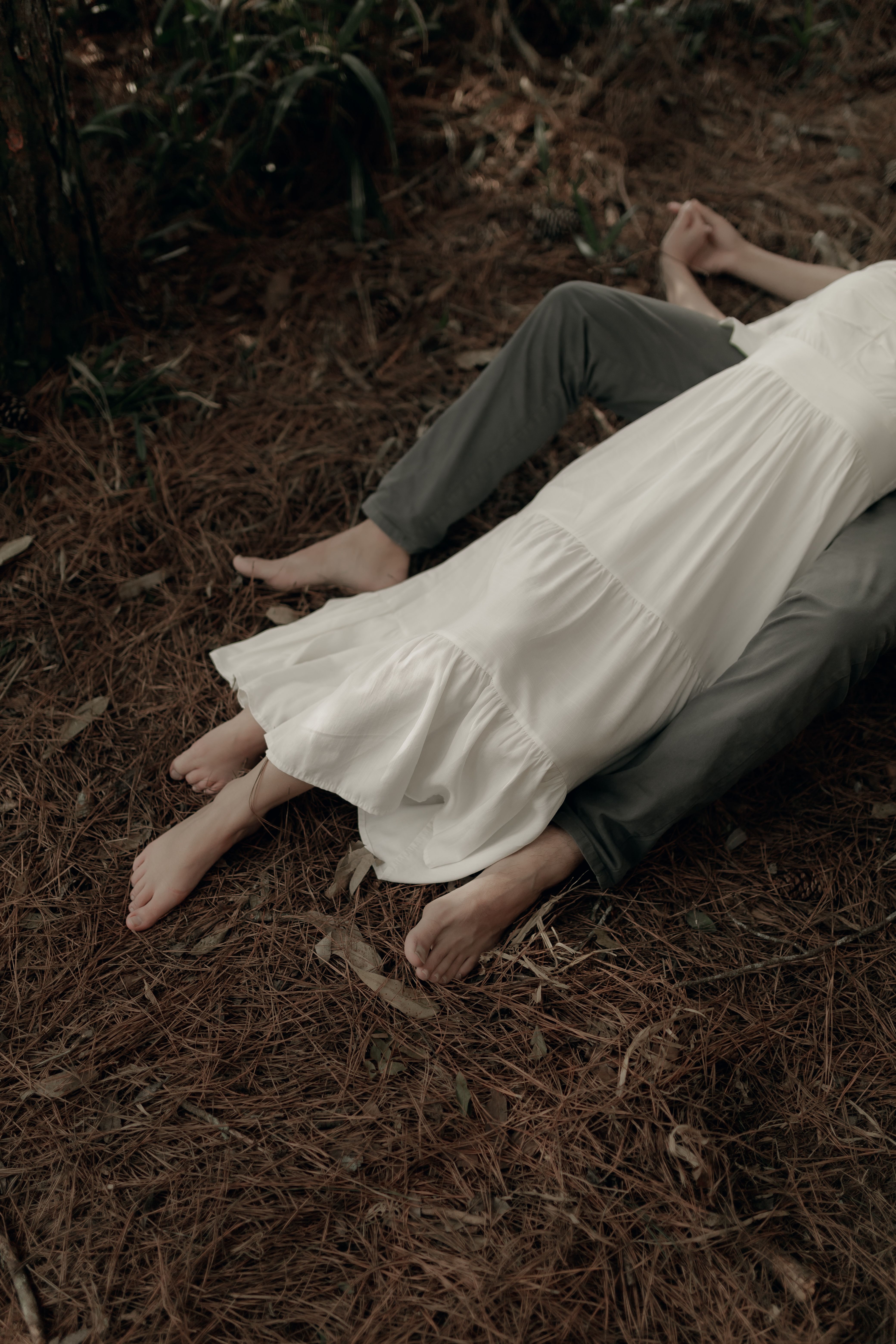 Couple in peaceful embrace lying on forest ground surrounded by nature.