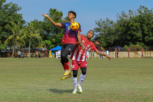Two youth soccer players compete fiercely for the ball in an outdoor field.