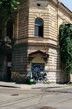 Rustic building corner with vibrant graffiti in Tbilisi, Georgia, showcasing urban street art.