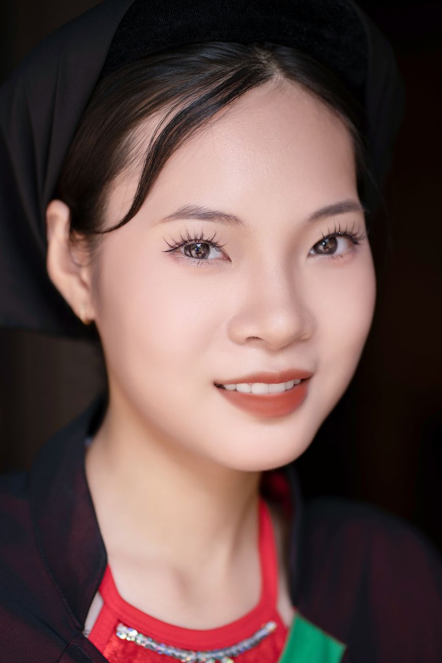 Close-up of smiling woman wearing traditional clothing and headscarf indoors.