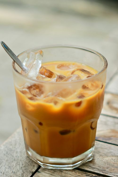 Free Glass of iced coffee with ice cubes and spoon, set outdoors on a sunny day. Stock Photo