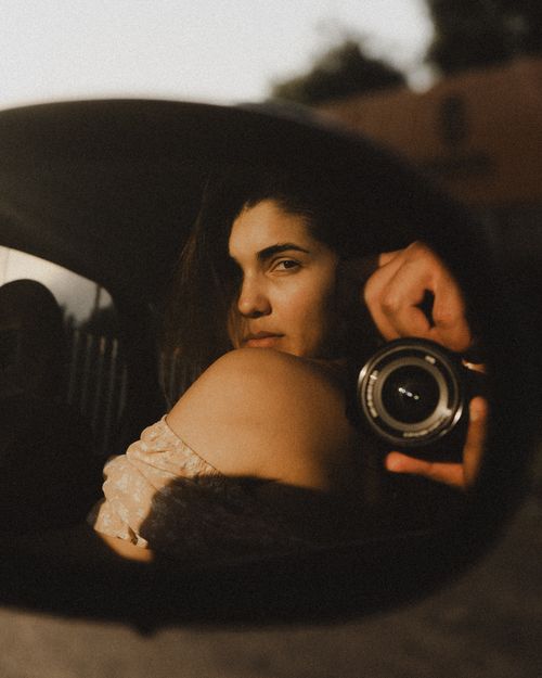 Free Artistic photo of a woman reflected in a car side mirror with a camera focus. Stock Photo