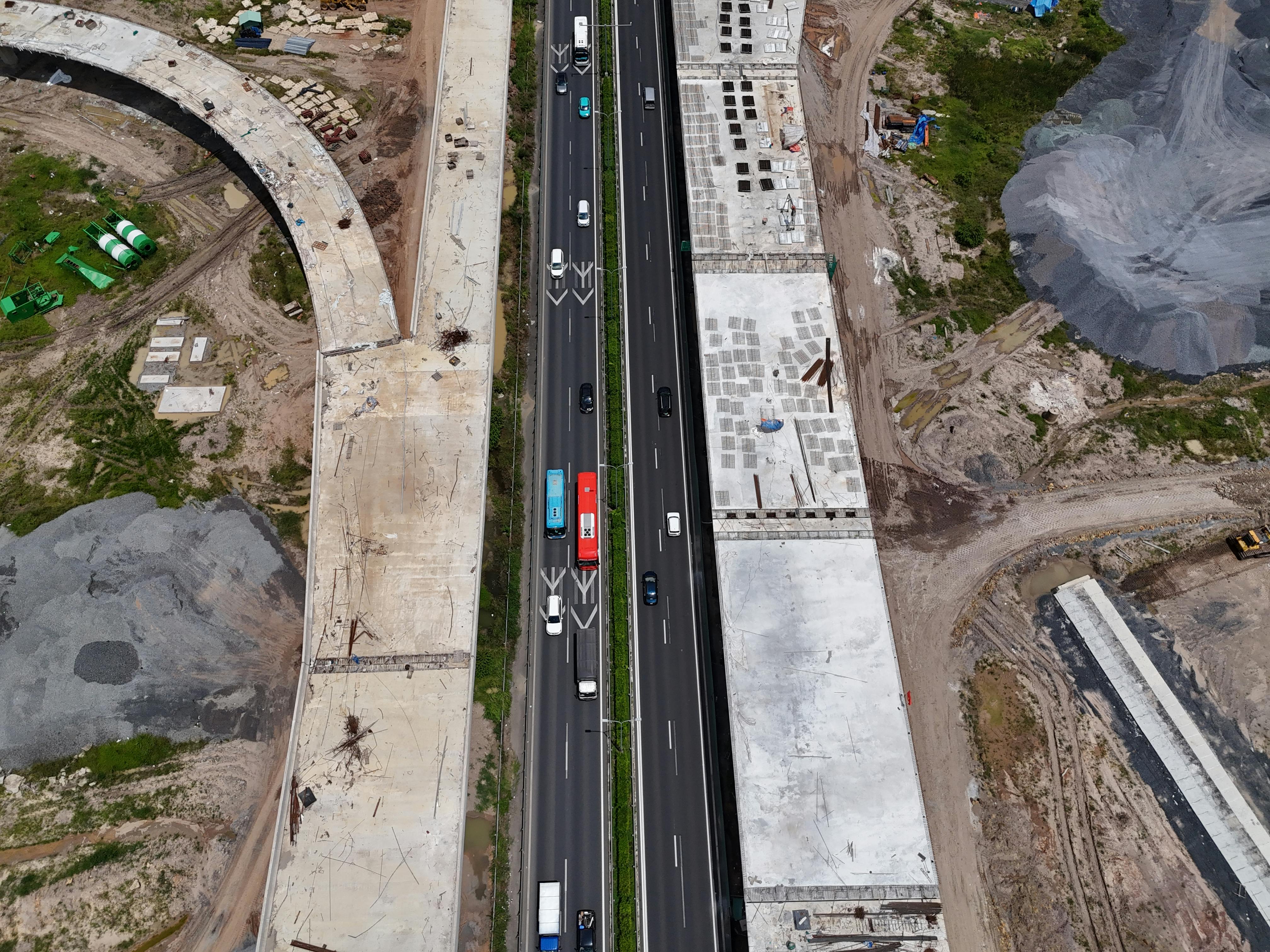 An aerial shot of a busy highway flanked by construction sites, showcasing urban development.
