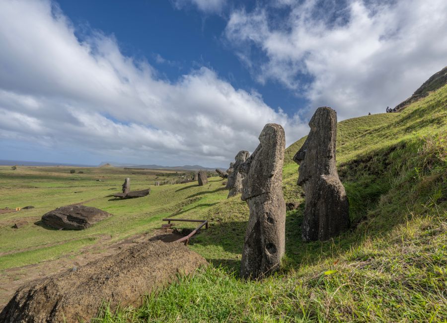 Explore the iconic Moai statues on Easter Island, Chile, surrounded by vast green landscapes and a bright blue sky.
