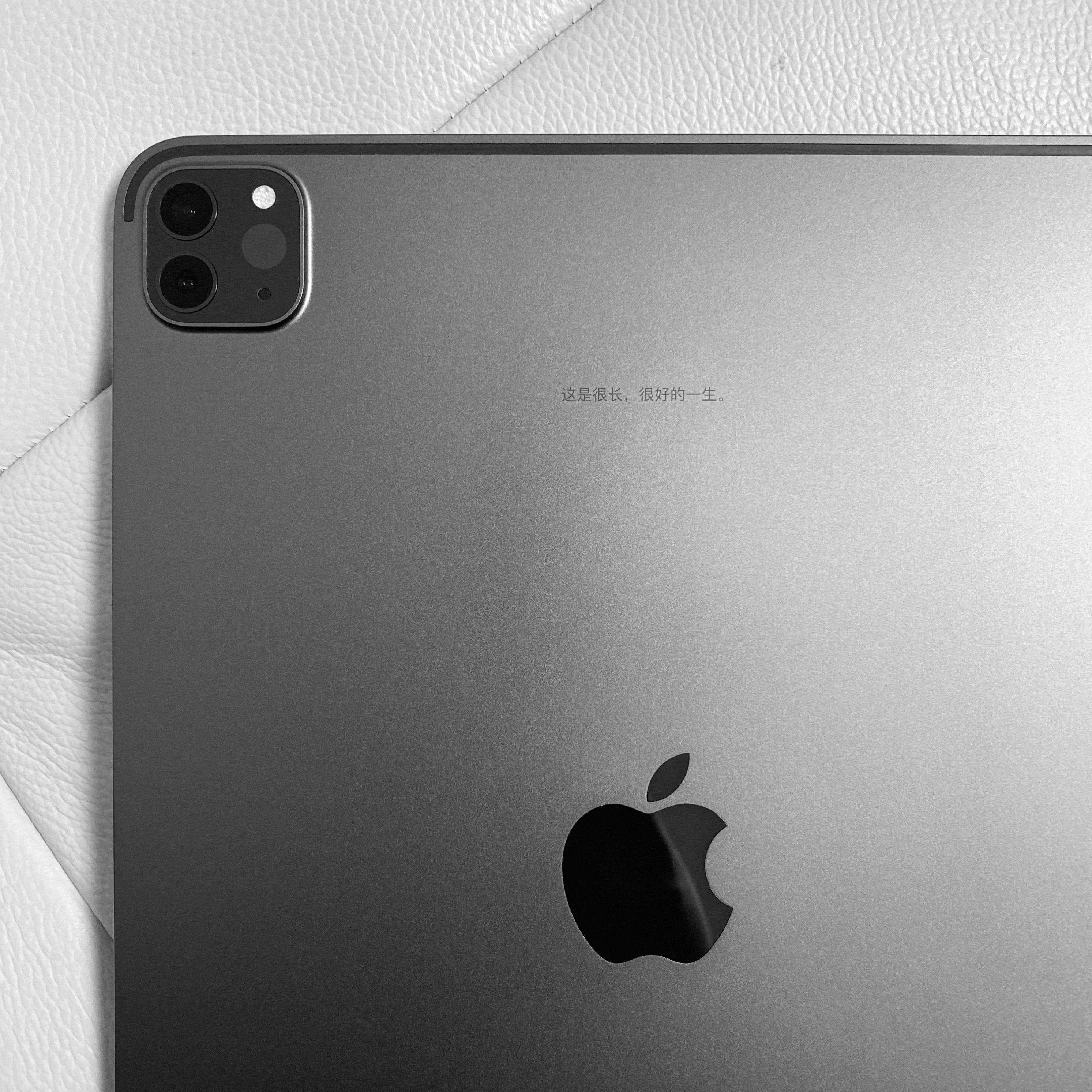 Silver tablet close-up showing dual camera module on white textured background.