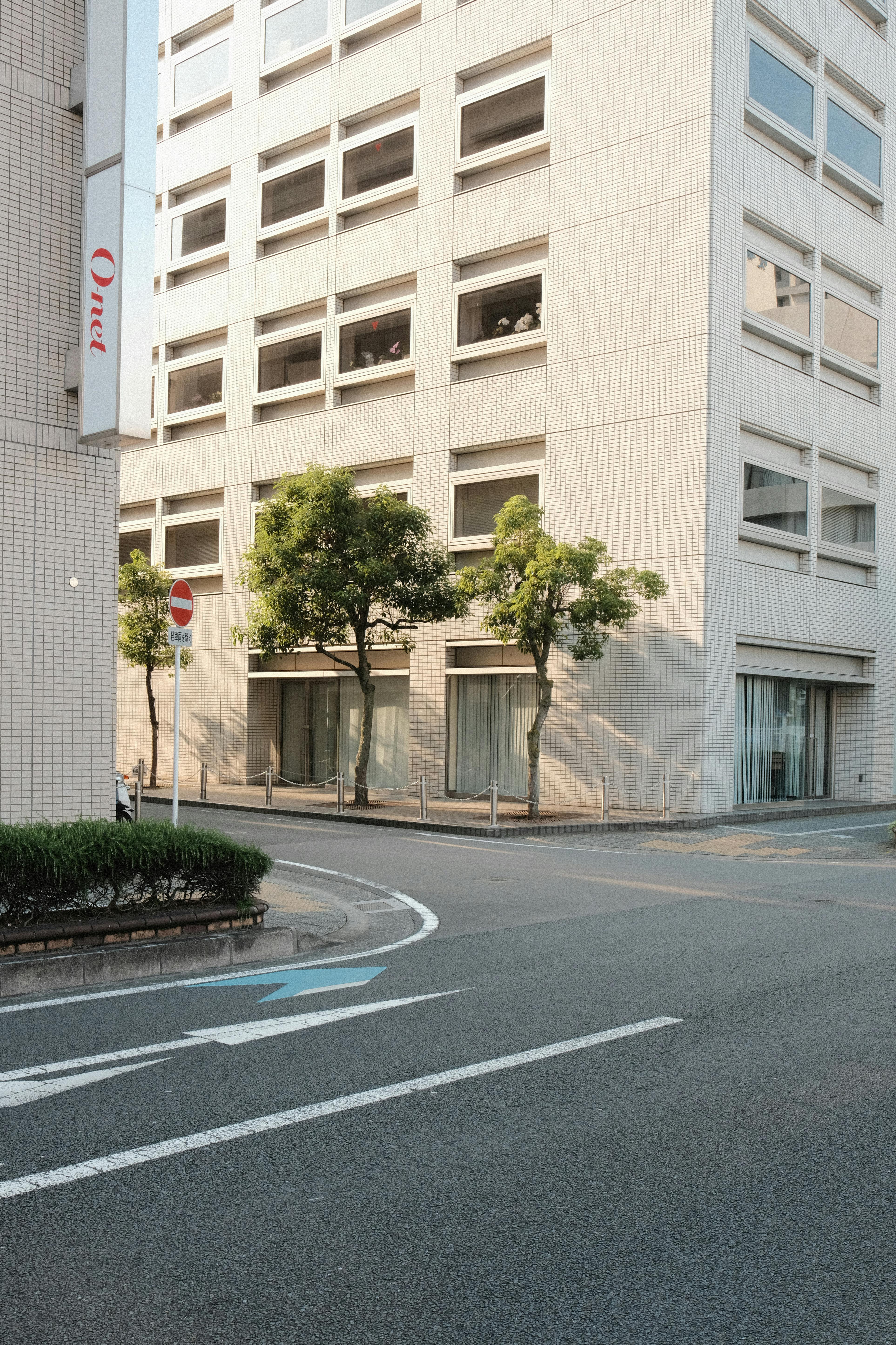 A contemporary office building facade with surrounding street and trees.