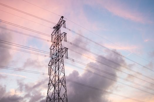 Photo by Yan Zhang High voltage power lines silhouetted against a vivid sunset sky with clouds.