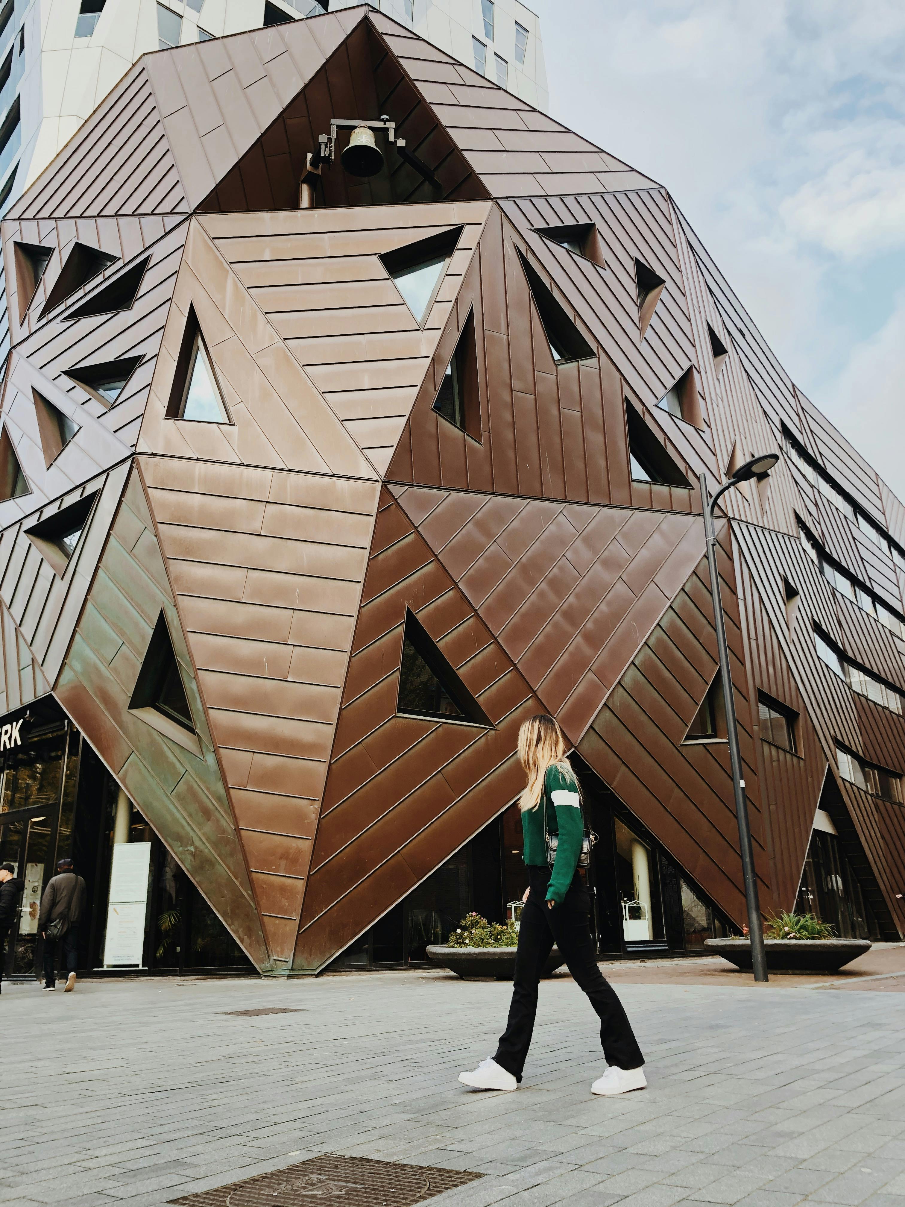 一名妇女走过一座具有引人注目的几何设计的现代建筑立面