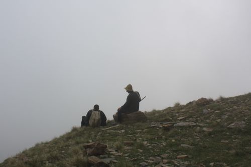 Free Two hikers sit on a foggy mountain slope, surrounded by mist and tranquility. Stock Photo