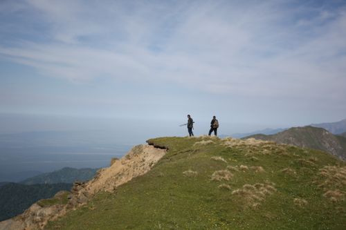 Free Two hikers traverse a mountain ridge under a vast blue sky, capturing the essence of adventure. Stock Photo