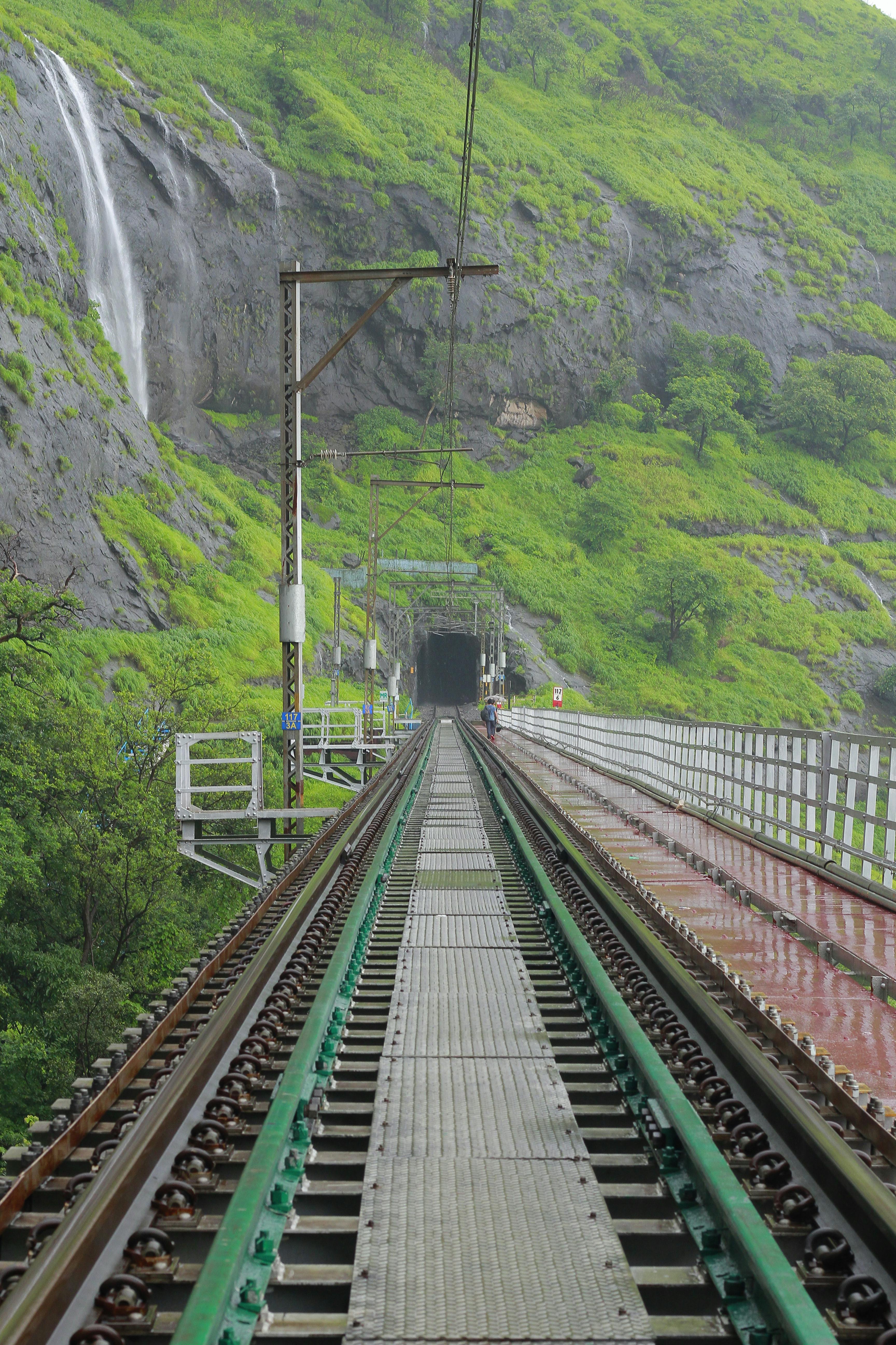 Railway track leading into a tunnel in the green hills of Maharashtra, India. | Indian Village Development