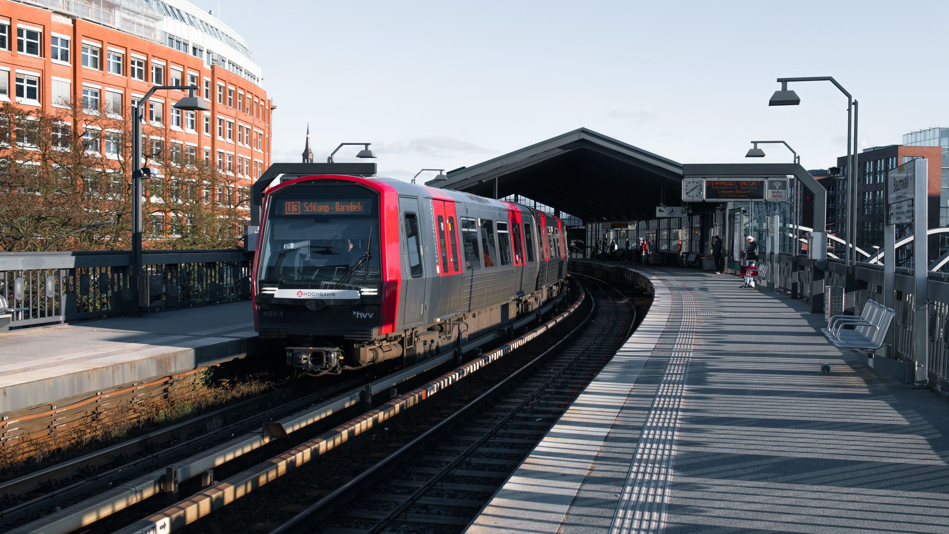 A commuter train arrives at a modern outdoor station in Hamburg, Germany.