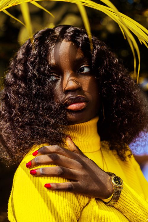 Free Striking photo of a stylish woman in a bright yellow sweater with bold red nails, captured outdoors in Nigeria. Stock Photo