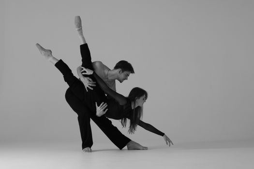 A dynamic ballet dance pose featuring a male and female dancer in a monochrome setting.