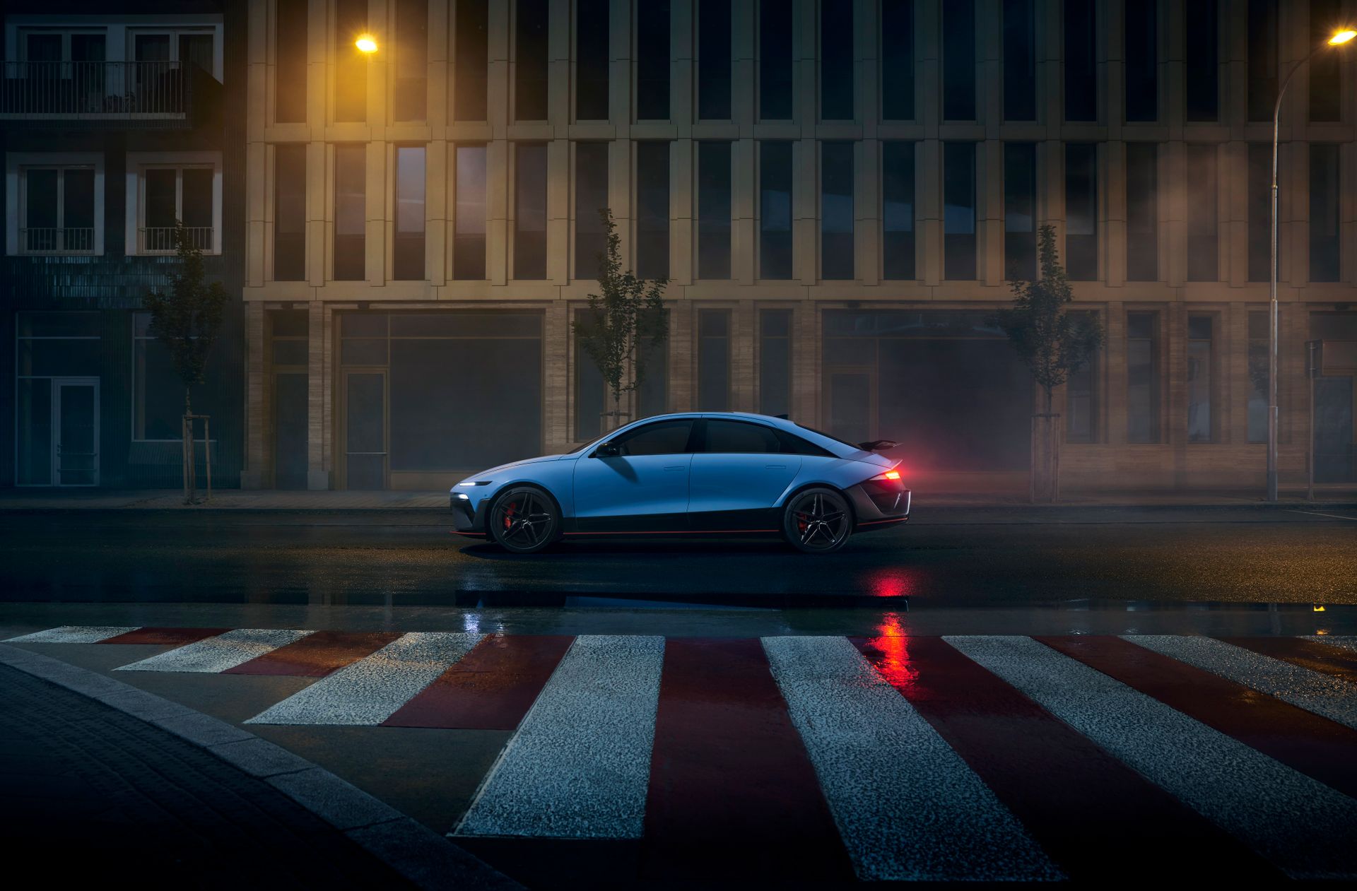 Modern electric vehicle parked on a wet city road under streetlights at night.