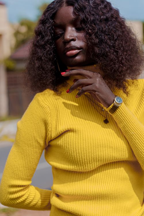 Free Confident woman in a yellow sweater poses outdoors on a sunny day, exuding elegance. Stock Photo