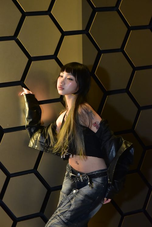 Free Portrait of a stylish young woman with tattoos in front of a honeycomb wall. Stock Photo