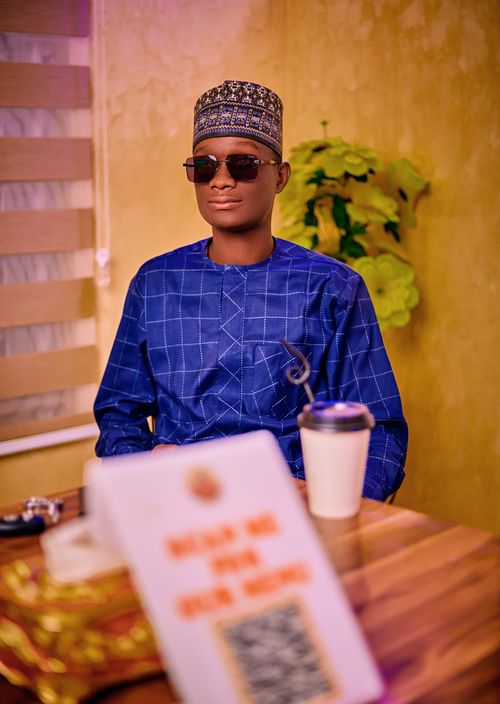 Free Man in a blue traditional outfit and sunglasses indoors, casual setting. Stock Photo