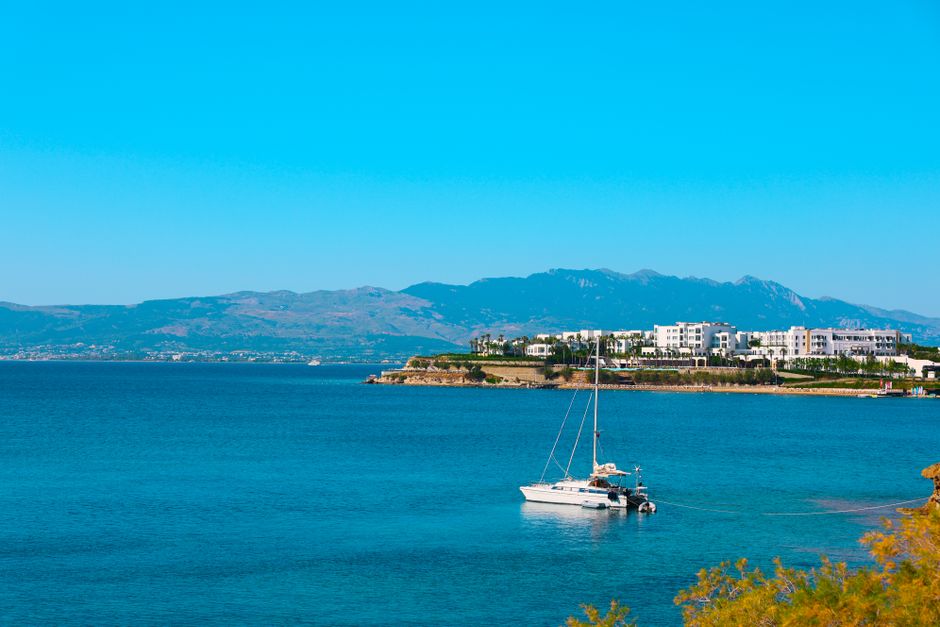 Ultimate Semi-Private Sailing Cruise to Iconic Bays (Shore-Ex Top Choice) Review: Your Ultimate Rhodes Sailing Adventure Review 2026 - A tranquil scene of a sailboat on the blue waters of a Mediterranean coastline with mountains in the background.