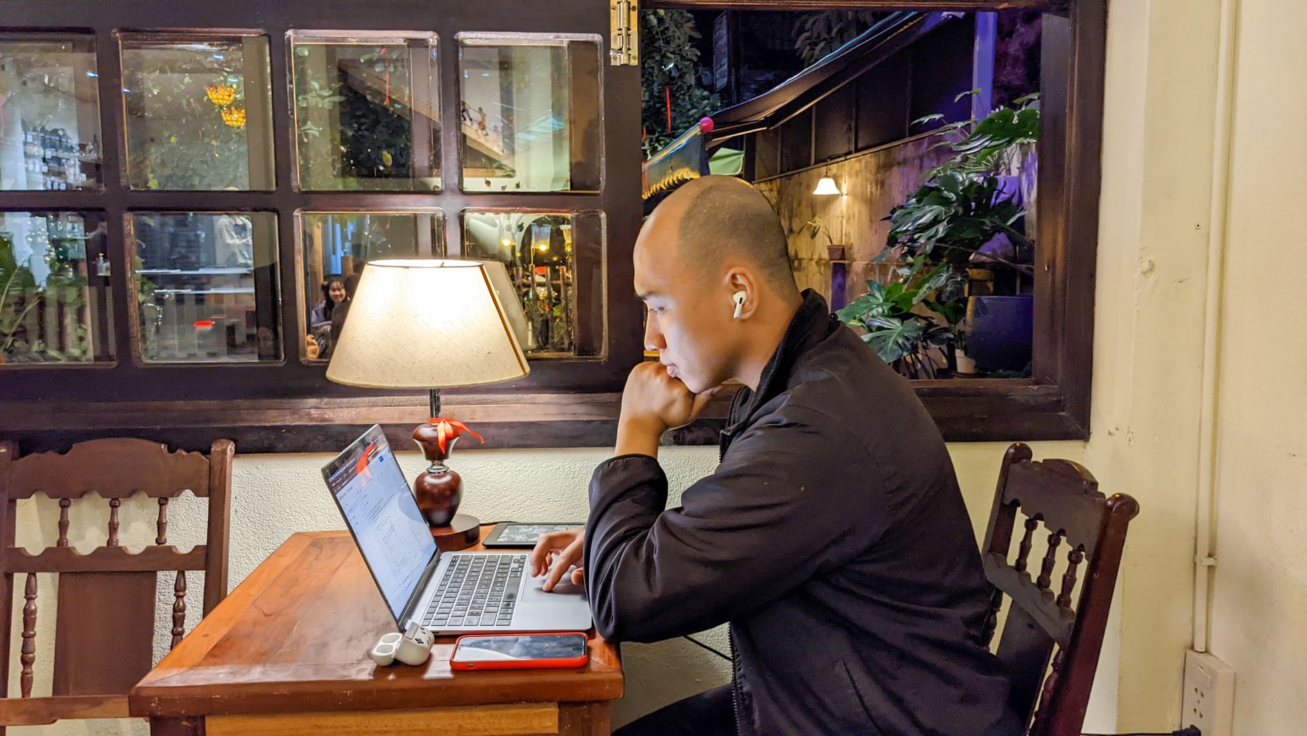 A person working on a laptop in a cozy Vietnamese cafe setting, creating a relaxed ambiance.